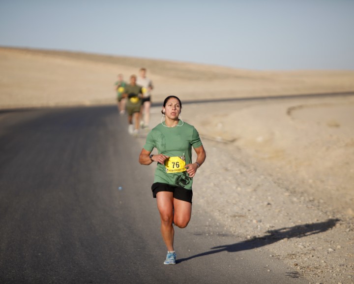 A runner on an asphalt track in a desertic region.